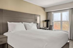 a large white bed in a room with a window at Residence Inn by Marriott Davenport in Davenport