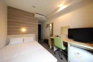 Smile Hotel Osaka Tennoji في أوساكا: غرفة بها سرير ومكتب وبه جهاز كمبيوتر