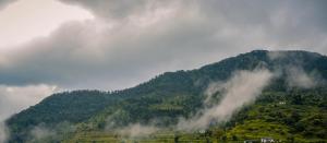 una montaña cubierta de niebla y nubes en el cielo en The Janvi Camping Resort en Nainital