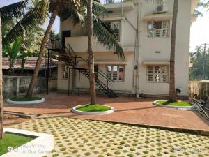 un edificio con due palme di fronte di His Grace Holiday Home - Nr to Malpe Beach a Udupi