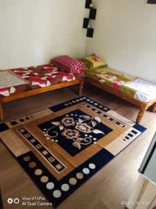a room with two beds and a rug on the floor at His Grace Holiday Home - Nr to Malpe Beach in Udupi