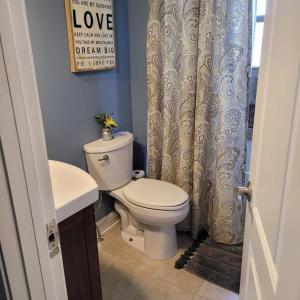 a bathroom with a toilet and a shower curtain at Cozy Cottage in Louisville in Louisville