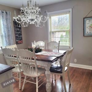 a dining room table with white chairs and a chandelier at Cozy Cottage in Louisville in Louisville