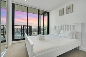 a bedroom with a white bed and large windows at Wake Up in Front of Water Bay Beckons- 2B2B1C in Melbourne