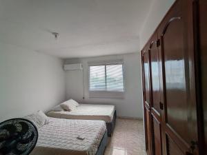 Duas camas num pequeno quarto com uma janela em Apartamento en Cartagena cerca del aeropuerto em Cartagena das Índias