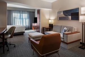 a hotel room with a bed and a couch and a desk at Courtyard Long Beach Airport in Long Beach