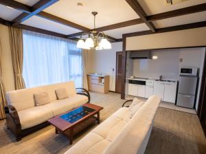 ein Wohnzimmer mit einem Sofa und einem Tisch in der Unterkunft Le Nessa Jyogasaki in Ito