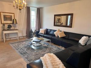 uma sala de estar com um sofá preto e uma mesa em Entire villa only 35 minutes from Puy du Fou em La Chapelle-Saint-Étienne