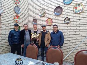 a group of people holding a cake in front of a wall at Guest House "AN" & Teahouse in Bukhara