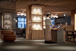 a woman standing at a counter in a lobby at The Chapter Kyoto, a Tribute Portfolio Hotel in Kyoto