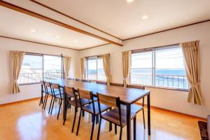 a dining room with a table and chairs and windows at Minamichita Seaside Villa - Vacation STAY 14160 in Minamichita