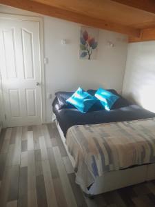 a bedroom with a bed with blue pillows on it at Departamento con acceso independiente - English spoken in Punta Arenas