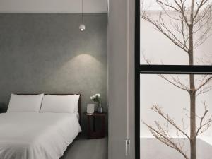 ein Schlafzimmer mit einem weißen Bett und einem Fenster in der Unterkunft 廣發寓所 in Tainan