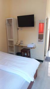 Schlafzimmer mit einem Bett und einem Schreibtisch mit einem Flachbild-TV in der Unterkunft Angler Family Guest House in Karangtengah