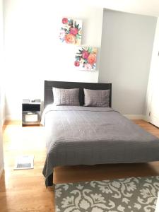 um quarto com uma cama com uma colcha cinzenta e um tapete em Renovated, 10 Min from the city em Boston