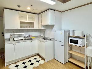 kuchnia z białymi szafkami i lodówką w obiekcie ChaenHaus w Seulu