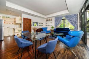 a living room with blue chairs and a glass table at Kamala Beach Estate Resort - SHA Extra Plus in Kamala Beach