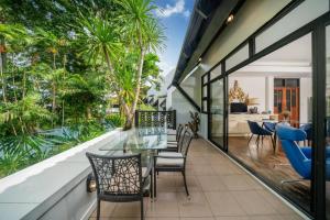 an open balcony with a glass table and chairs at Kamala Beach Estate Resort - SHA Extra Plus in Kamala Beach