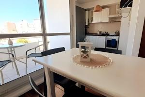 una cocina con una mesa y sillas blancas y una ventana en Hornera San Juan - Luminoso Apartamento con Balcón en Rosario