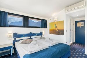 a bedroom with a blue and white bed and windows at Bike & Wind Hotel Villa Maria - Happy Rentals in Nago-Torbole