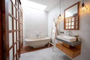 a bathroom with a tub and a sink and a mirror at Omkara Dharman Ubud Villa By Omkara Experience in Ubud