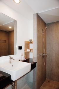 een badkamer met een wastafel en een douche met een spiegel bij Peppery Hills in Chiang Mai