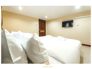 1 dormitorio con 1 cama con almohadas blancas y TV en The Crystal Ranong No201, en Ban Lum Than