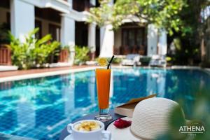 una bebida sentada en una mesa junto a una piscina en Athena Hotel en Pakse