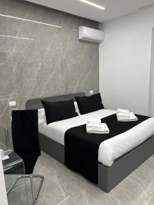 - une chambre avec un lit noir et blanc et une chaise dans l'établissement White Elegance Luxury B&B Caserta, à Caserte