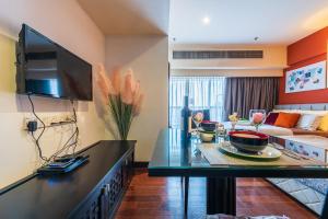 een woonkamer met een bank en een tv aan de muur bij Resort Suite 6pax Homestay at Sunway Pyramid&Sunway Lagoon in Petaling Jaya