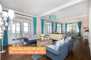 Elle comprend un salon doté d'un mobilier bleu et de rideaux bleus. dans l'établissement Villa Hạng Sang Đà Lạt - Gần Hồ Xuân Hương Gần Chợ Đà Lạt, à Xuan An