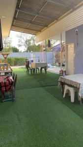 a patio with a ping pong table and benches on grass at เอ็มยูโฮมรีสอร์ท in Ban Khlong Lam Hin