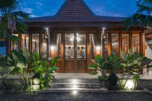 dom z drewnianymi drzwiami i roślinami w obiekcie Gria Kerten w mieście Surakarta