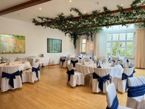 a room with white tables and chairs with blue bows at Hotel Garni Schwane in Meßstetten