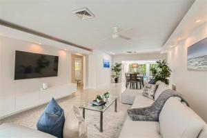 uma sala de estar com um sofá branco e uma televisão em Cozy House Lauderdale By the Sea em Fort Lauderdale