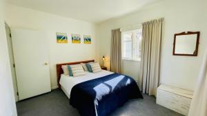 a bedroom with a bed with blue and white pillows at Stay on Glanmire in Wellington