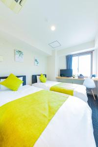 dwa łóżka w pokoju z żółto-białym w obiekcie JA Hotel Bentencho 弁天町 w Osace