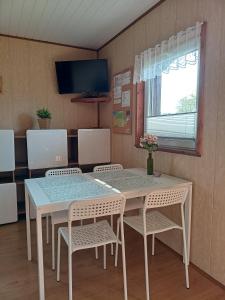 a dining room with a table and chairs and a tv at Domki WIKA 2 in Ustka