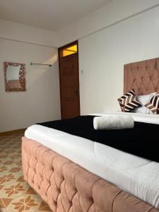 a bedroom with a large bed with a brown headboard at Silva-Mindvalley in Nakuru