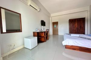 a bedroom with a bed and a desk and a television at Tara Apartment in Surat Thani