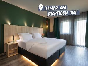a hotel room with a large bed and a sign at ACHAT Hotel Reilingen Walldorf in Reilingen