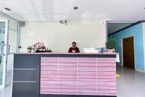 a woman sitting at a counter in a lobby at Tara Apartment in Surat Thani