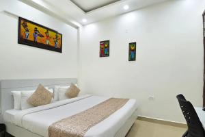 biała sypialnia z łóżkiem i obrazami na ścianie w obiekcie the indigo premium w mieście Noida