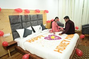mężczyzna i kobieta siedzący na łóżku z tortem w obiekcie Nirvana -A Balcony Rooms Hotel-A True View Of Mountains w mieście Manāli
