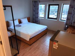 a small bedroom with a bed and two windows at โรงแรมควีนส์ (Queen) in Ban Tha Kham