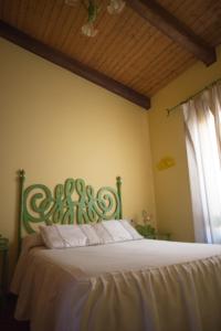 a bedroom with a bed with a green headboard at Apartamentos Rurales Arco de Trajano in Alcántara