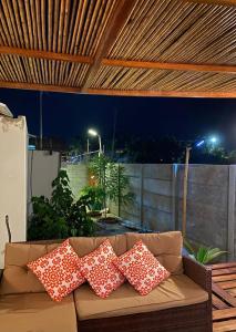 a couch with pillows on a patio at night at Casa Pepita in Máncora