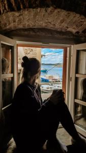 una mujer sentada en una ventana mirando hacia el agua en City Rooms Šibenik, en Šibenik