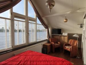 1 dormitorio con cama roja, silla y ventanas en Home Comfortable holiday residence, en Veen