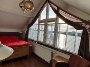 1 dormitorio con cama roja y ventana grande en Home Comfortable holiday residence, en Veen